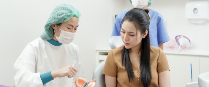 Tweezers placing a veneer over the front surface of a model of a tooth