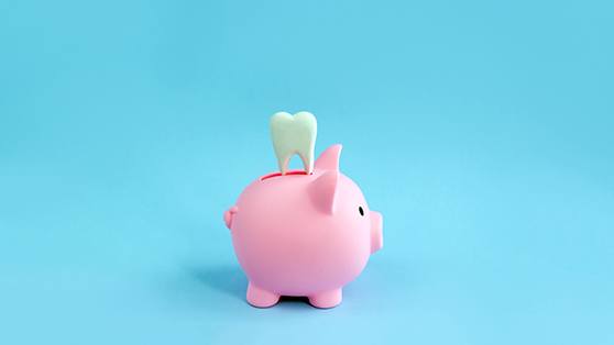 A decorative tooth sitting on top of a pink piggy bank