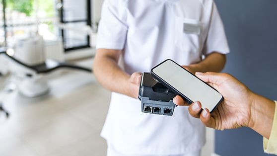 A woman using her smartphone to pay for her dental care
