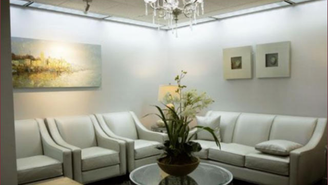 White couches and armchairs in comfortable waiting area of dental office