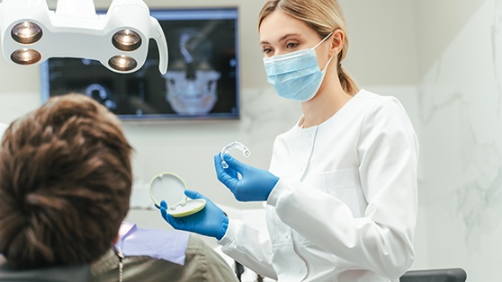 Dentist showing patient clear aligner in treatment room