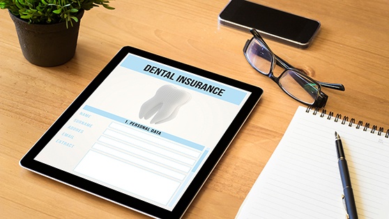 Dental insurance form on desk with glasses and notepad