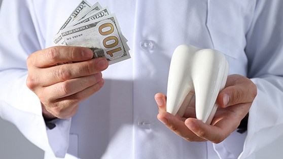 a dentist holding a model of a tooth