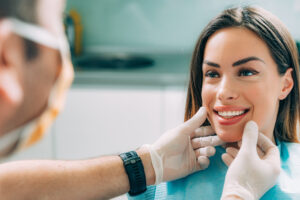 Young woman smiling in dentist's chair while having smile examined. 