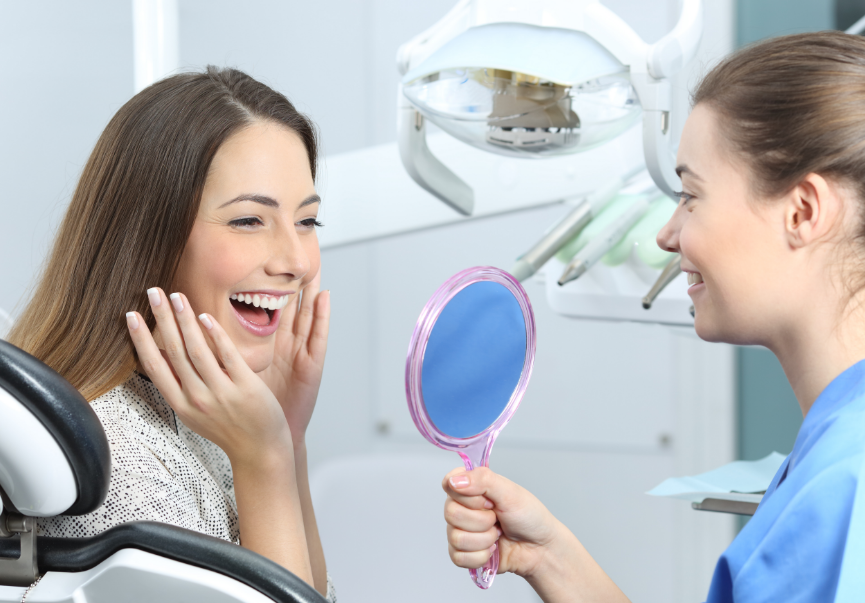 Dentist holding mirror for smiling teen in chair
