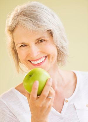 woman with dental implants eating an apple